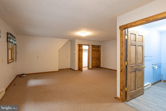 carpeted spare room featuring a baseboard radiator and a textured ceiling