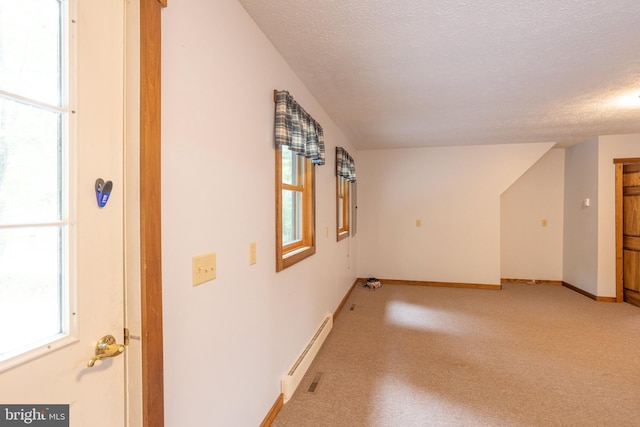 interior space with a wealth of natural light, baseboard heating, light carpet, and a textured ceiling