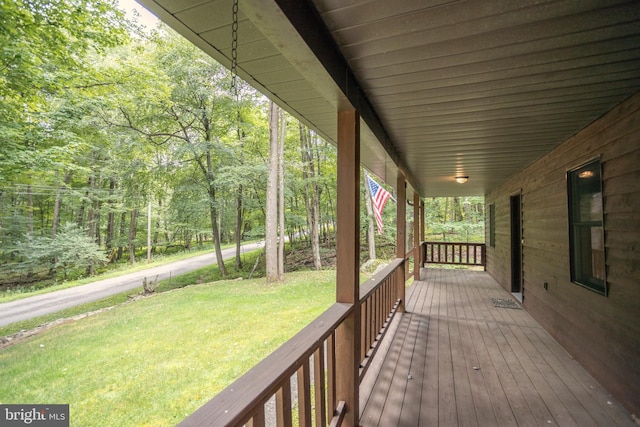 wooden deck featuring covered porch and a lawn