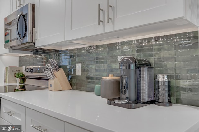 interior space featuring white electric stove, white cabinets, and decorative backsplash