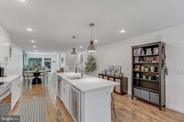 kitchen with light hardwood / wood-style flooring, sink, white cabinets, and a kitchen island with sink