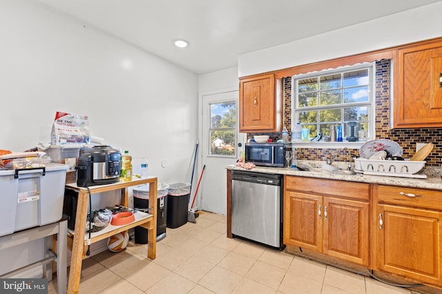 5120 Crittenden St, Hyattsville, MD 20781 - kitchen featuring dishwasher, backsplash, brown cabinetry, light stone countertops, and light tile patterned floors