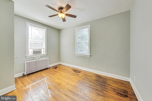 unfurnished room with light hardwood / wood-style floors, ceiling fan, radiator heating unit, and plenty of natural light