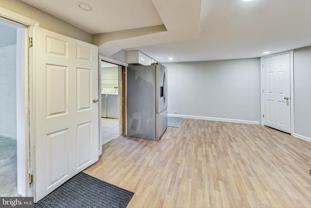 basement with light wood-type flooring, washer and dryer, and stainless steel fridge with ice dispenser