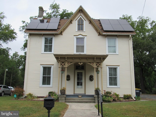 view of front of property featuring a front yard, solar panels, and a porch