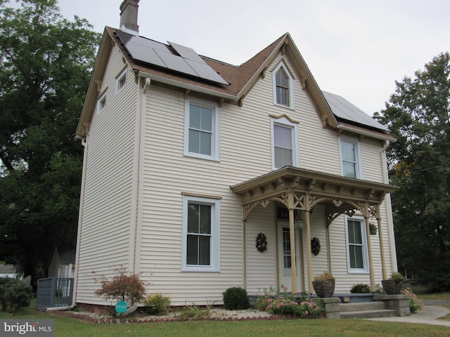 view of front facade featuring solar panels and a front yard