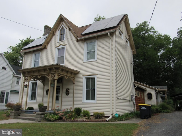 view of front of property with a front lawn, solar panels, and a porch