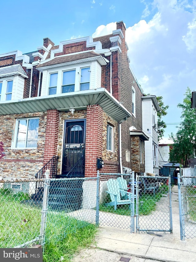 multi unit property featuring brick siding, a chimney, a fenced front yard, and a gate