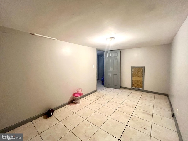 unfurnished room with light tile patterned floors and baseboards