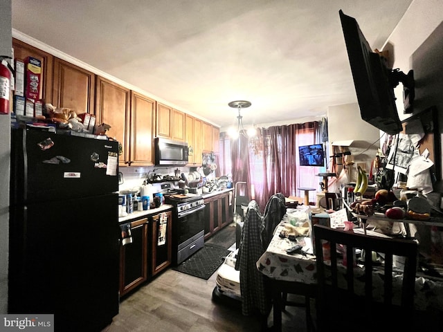 kitchen with light wood-type flooring, hanging light fixtures, and stainless steel appliances