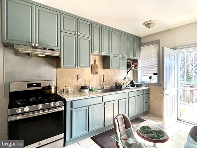 kitchen featuring light tile patterned flooring, a sink, light countertops, under cabinet range hood, and stainless steel gas stove