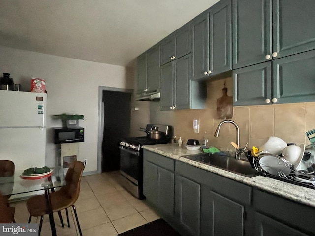 kitchen with stainless steel gas range oven, under cabinet range hood, a sink, freestanding refrigerator, and black microwave