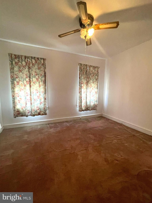 empty room featuring dark colored carpet, ceiling fan, and vaulted ceiling