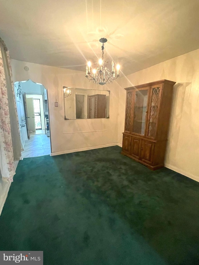 unfurnished living room with dark carpet and a chandelier