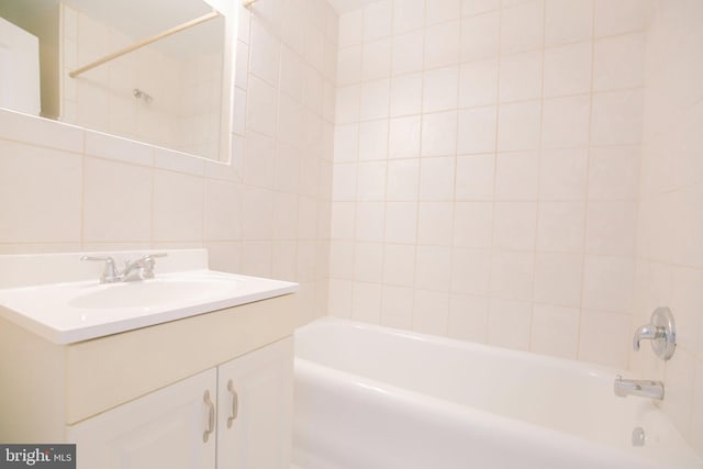 bathroom featuring tasteful backsplash, vanity, tiled shower / bath combo, and tile walls