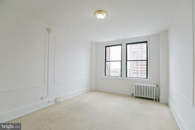 spare room with light colored carpet and radiator heating unit