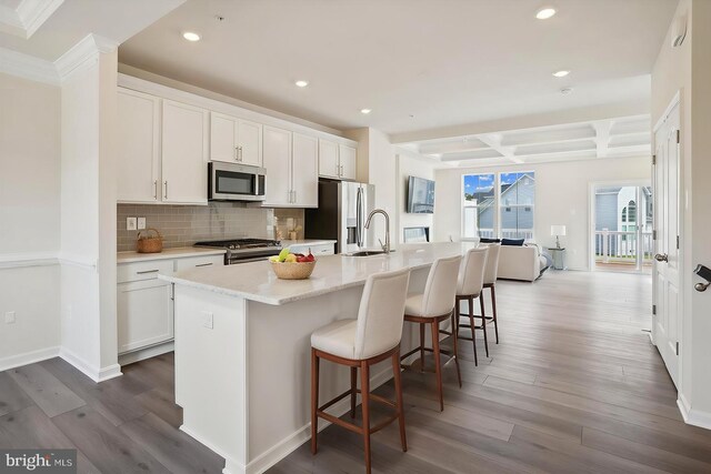 living room featuring beam ceiling, light hardwood / wood-style floors, coffered ceiling, and ornamental molding