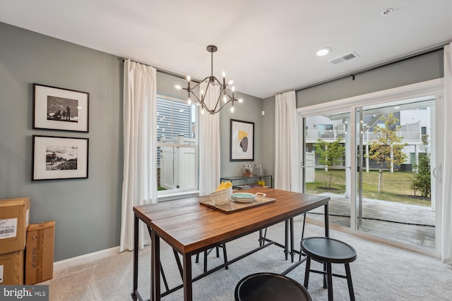 dining space with light carpet and a chandelier