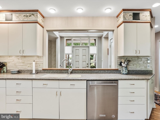 kitchen with white cabinets, sink, stainless steel dishwasher, wood-type flooring, and backsplash