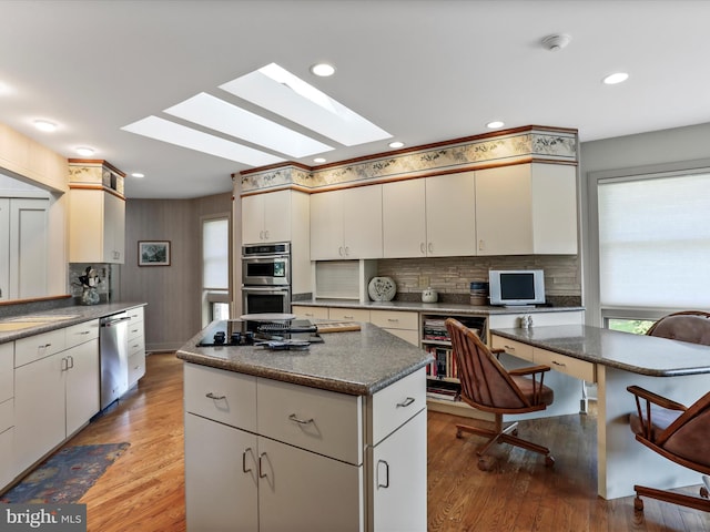 kitchen featuring wood-type flooring, white cabinets, appliances with stainless steel finishes, and a center island