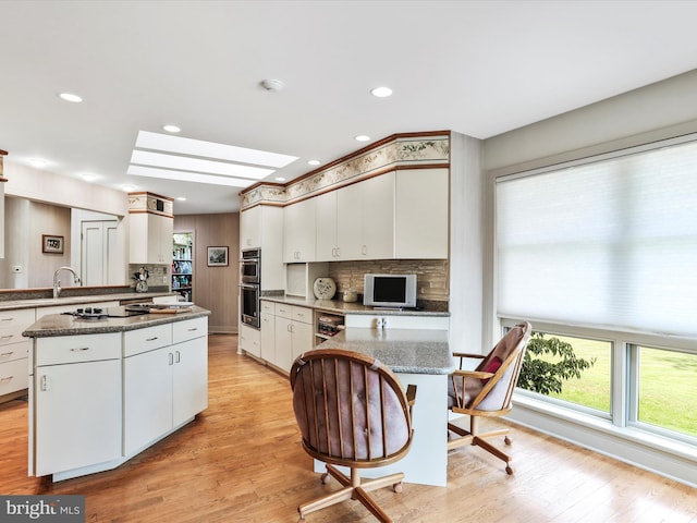 kitchen featuring a kitchen island, light hardwood / wood-style floors, tasteful backsplash, and white cabinetry