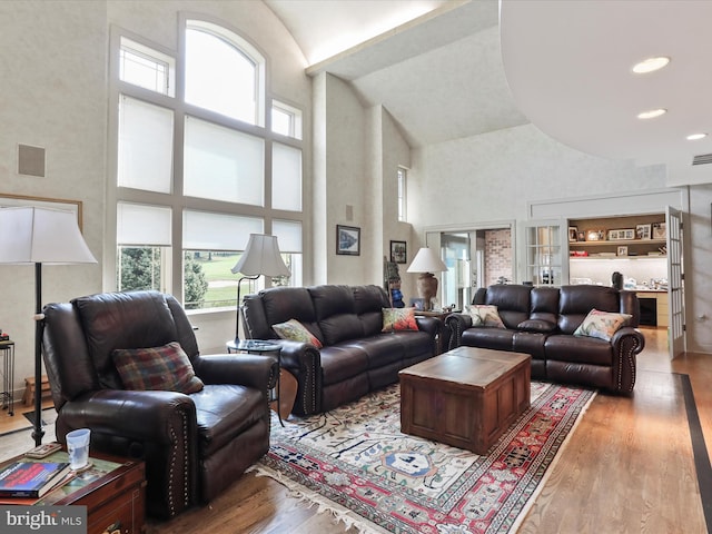 living room with a towering ceiling, light hardwood / wood-style floors, and a wealth of natural light