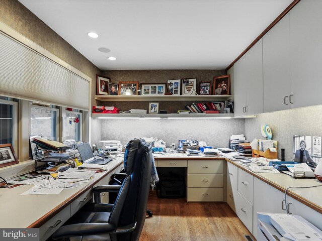 office area with ornamental molding, built in desk, and light hardwood / wood-style floors