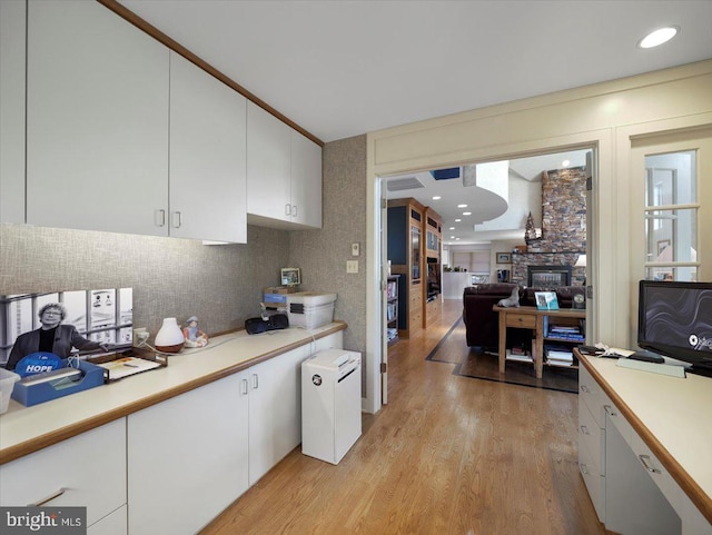 kitchen with light wood-type flooring, a fireplace, and white cabinetry