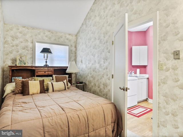 bedroom with ensuite bath, hardwood / wood-style flooring, and sink