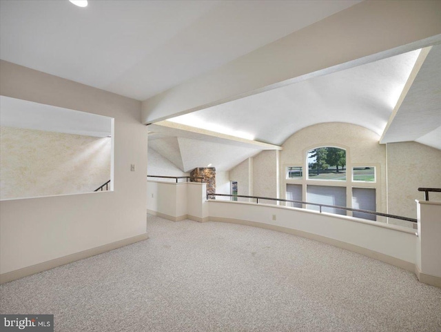 additional living space featuring vaulted ceiling and light colored carpet