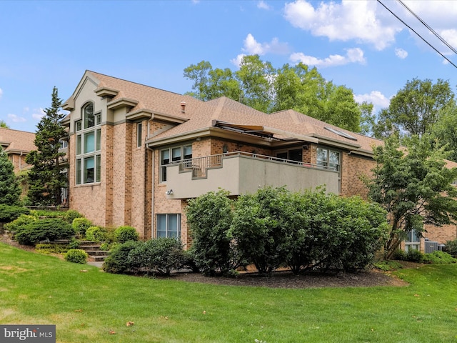 view of side of property with a balcony and a yard