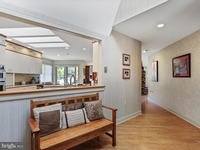 hallway featuring a skylight and light hardwood / wood-style flooring