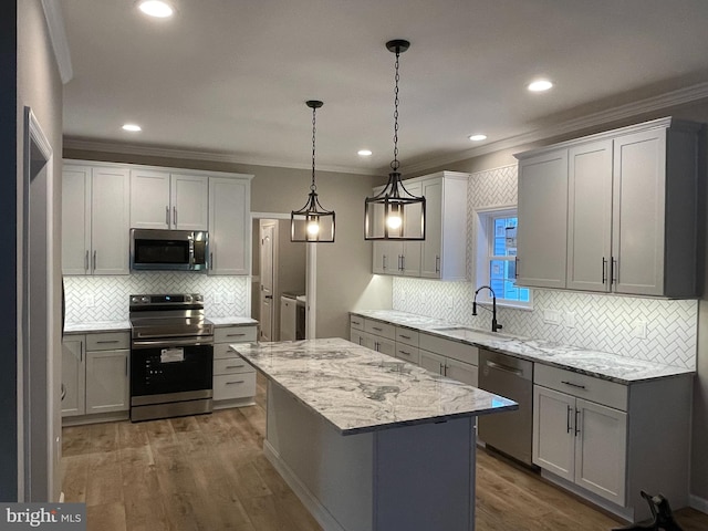 kitchen with crown molding, dark hardwood / wood-style flooring, a kitchen island, sink, and appliances with stainless steel finishes