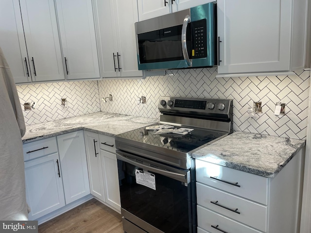 kitchen featuring light stone counters, stainless steel appliances, and white cabinets