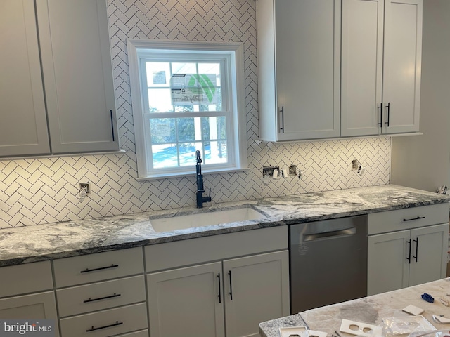 kitchen with stainless steel dishwasher, light stone counters, sink, and backsplash