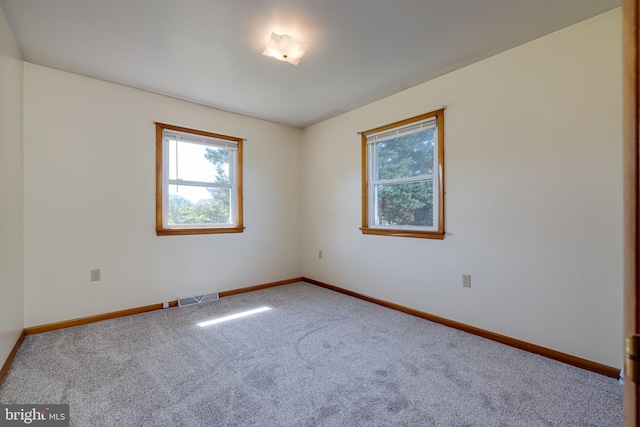 carpeted empty room with visible vents, baseboards, and a healthy amount of sunlight