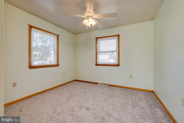 carpeted empty room featuring visible vents, a ceiling fan, and baseboards