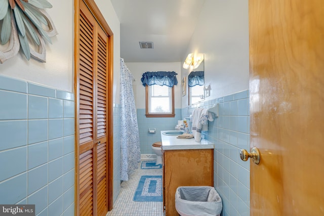 bathroom featuring vanity, a wainscoted wall, visible vents, tile patterned flooring, and tile walls