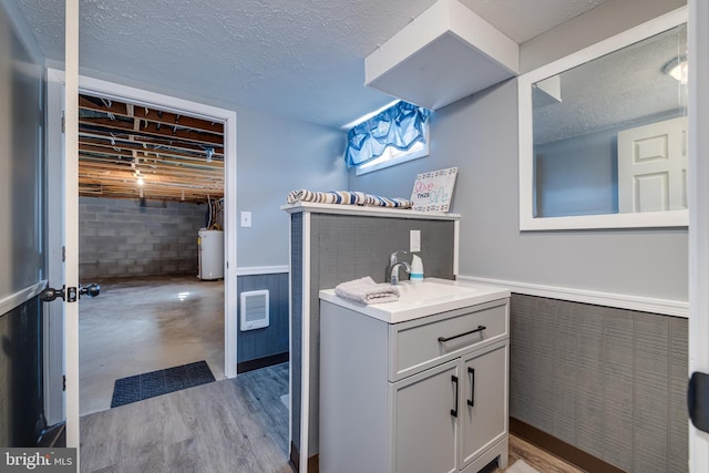 bathroom with wainscoting, gas water heater, a textured ceiling, and vanity