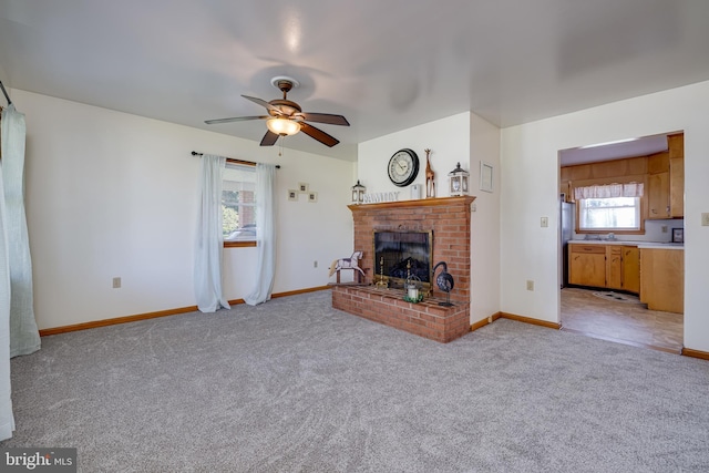 unfurnished living room featuring baseboards, light colored carpet, a brick fireplace, and ceiling fan