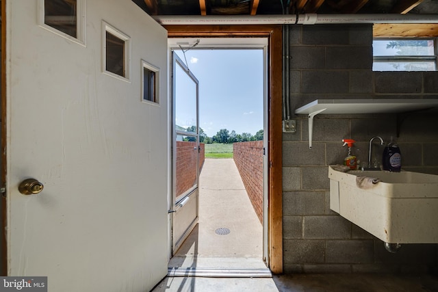 doorway to outside featuring a sink and concrete block wall