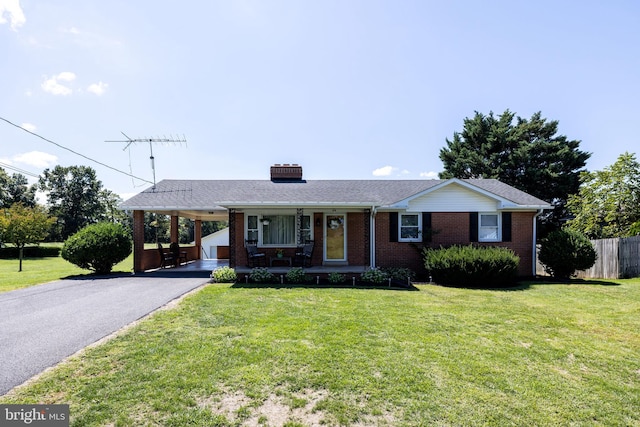 single story home featuring brick siding, fence, a front yard, a carport, and driveway