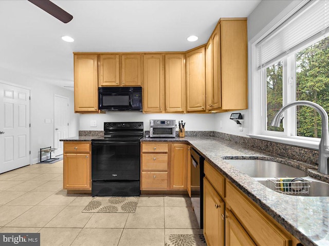 kitchen with black appliances, dark stone countertops, sink, and light tile patterned floors