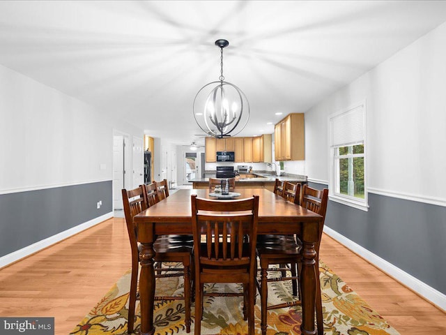 dining room featuring sink, light hardwood / wood-style flooring, and a chandelier