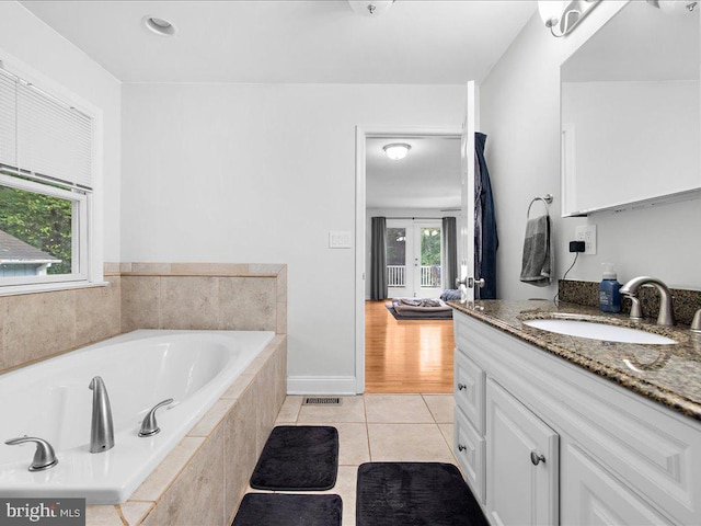 bathroom featuring a relaxing tiled tub, tile patterned floors, and vanity