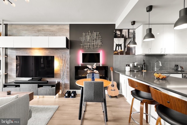 kitchen with decorative light fixtures, white cabinets, and light hardwood / wood-style flooring