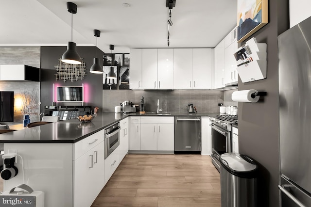 kitchen featuring stainless steel appliances, decorative light fixtures, kitchen peninsula, and white cabinetry