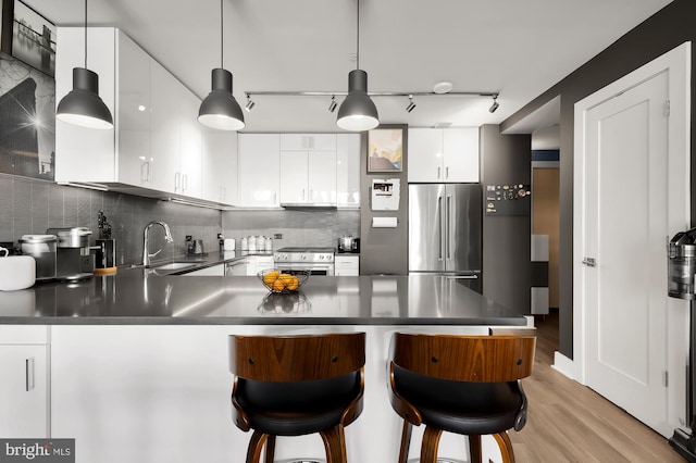 kitchen with kitchen peninsula, stainless steel appliances, sink, white cabinetry, and light wood-type flooring