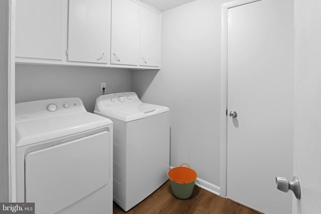 laundry area featuring dark hardwood / wood-style floors, washing machine and clothes dryer, and cabinets