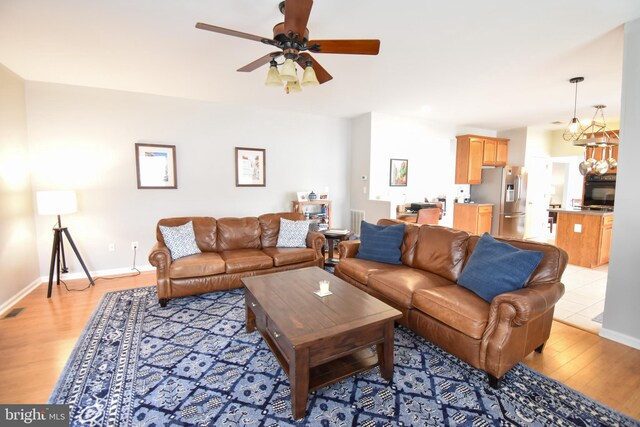 living room with light hardwood / wood-style flooring and ceiling fan with notable chandelier